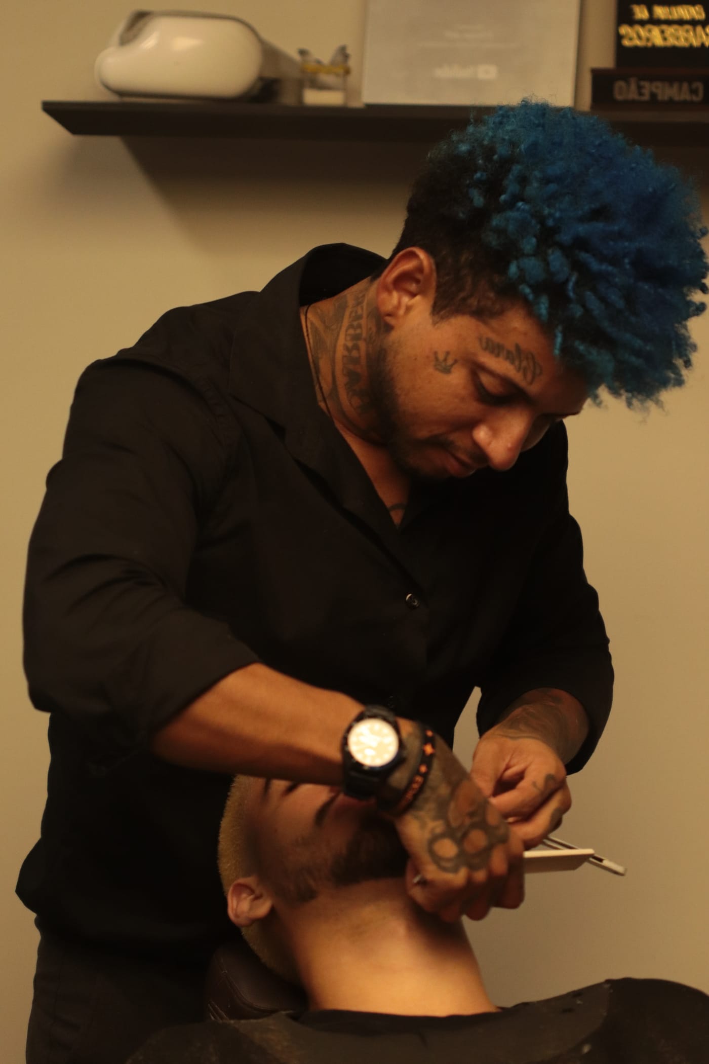 Barbeiro aparando o bigode de um cliente na MYL Barber Clinic